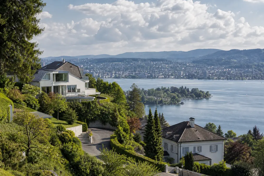 Wohnhäuser an einem Hang über dem Zürichsee mit Blick auf das Wasser
