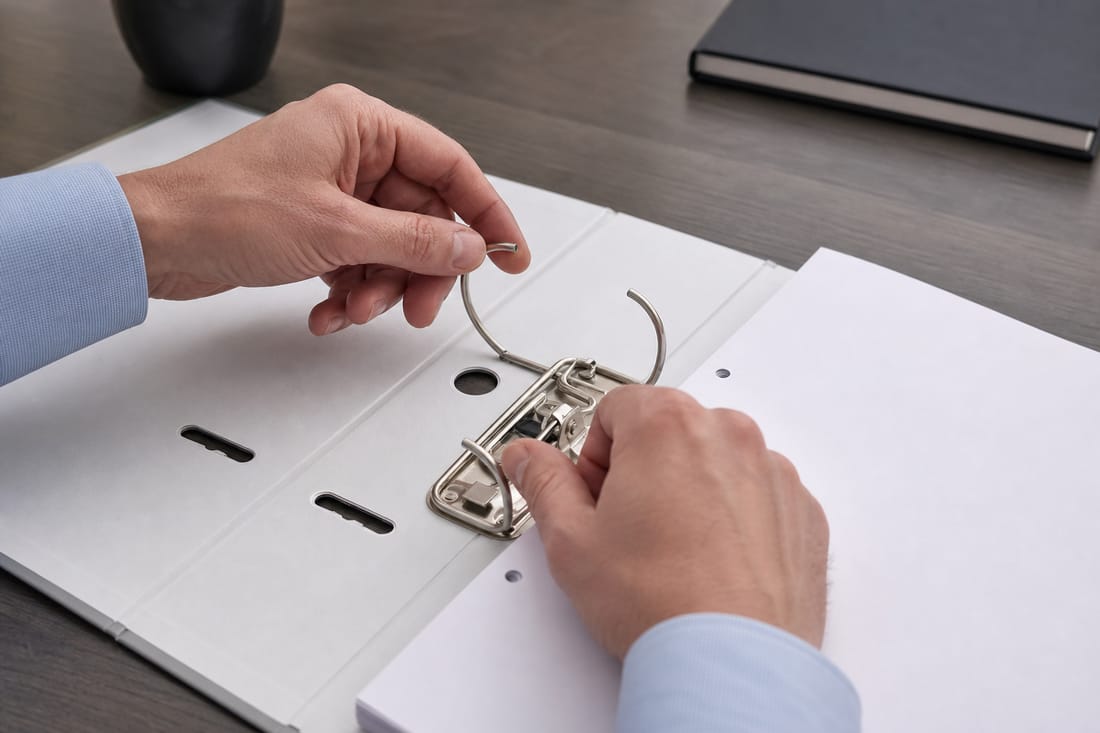Beispiel: Hände öffnen die Ringe eines leeren Dokumentenordners